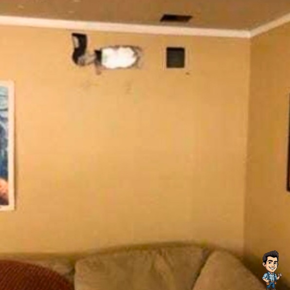 Living room wall with a hole near the ceiling before ceiling and wall repair